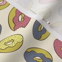 Pink, blue, yellow doughnuts (donuts), creamy yellow background