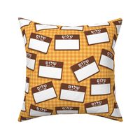 Scattered Hebrew 'hello my name is' nametags - brown on yellow/orange gingham