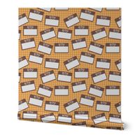 Scattered Hebrew 'hello my name is' nametags - brown on yellow/orange gingham