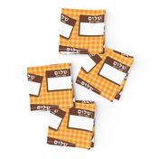 Scattered Hebrew 'hello my name is' nametags - brown on yellow/orange gingham