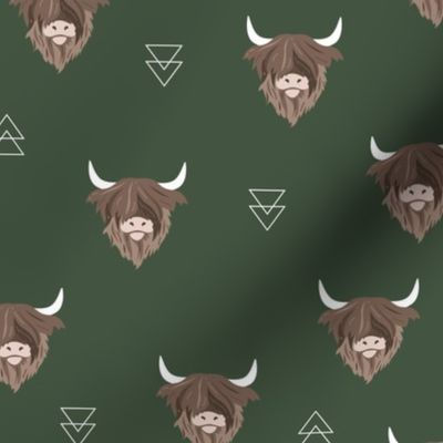 Sweet highlands with white horns and fuzzy hair highland cows rust brown on deep forest green