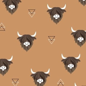 Sweet highlands with white horns and fuzzy hair highland cows rust brown on caramel camel beige