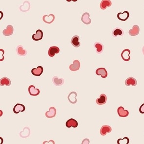 Scattered Hearts in red and pink on an off white cement background