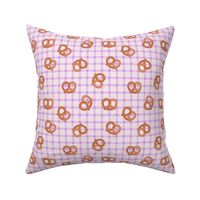 Tossed pretzels on traditional tartan table cloth plaid german food oktoberfest theme lilac blush