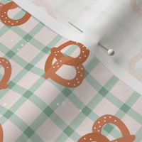 Tossed pretzels on traditional tartan table cloth plaid german food oktoberfest theme sage green on ivory beige