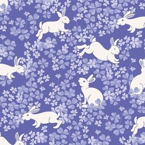 White Bunny Rabbits Hoping in a Field of Purple and Lilac Clover and Flowers