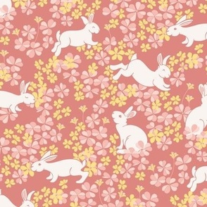 White Bunny Rabbits Hoping in a Field of Pink Clover and Yellow Flowers