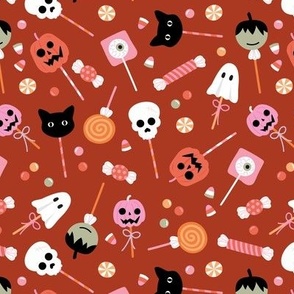 Colorful cutesy halloween lollipop - candy and sweets with skulls pumpkins ghosts cats and bloody eyes on vintage brick red 