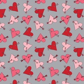 Pink and red hearts with arrows outlined and tossed on gray