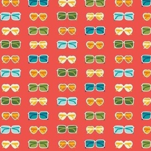 Colorful sunglasses in various shapes on red - summer fabric, home decor
