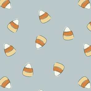 Large hand drawn scattered candy corn in yellow, burnt orange, and cream on a cornflower blue background
