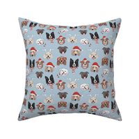 Christmas dogs - cute dressed up holiday puppies with antlers santa hats candy cane and sinter scarf and mittens on light blue 