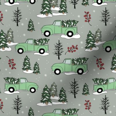 Driving home for Christmas - Winter wonderland christmas pine trees and pick up cars driving in the forest mint on gray