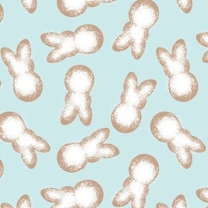 Little minimalist Easter bunnies - baked spring cookies powdered sugar on cookie dough on soft turquoise blue 