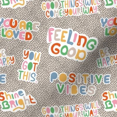 Positive vibes and happy affirmation stickers - freehand quote rainbow text design to cheer you up on tiny spots black on sand