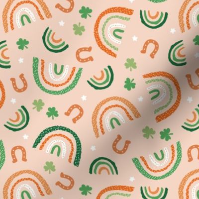 St Patrick's Day rainbows and lucky horse shoe stars and shamrock leaves orange pink lilac green on warm blush peach orange