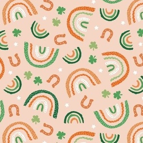 St Patrick's Day rainbows and lucky horse shoe stars and shamrock leaves orange pink lilac green on warm blush peach orange