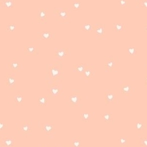 Scattered love hearts Valentine's Day in cream on light peach - SMALL SCALE