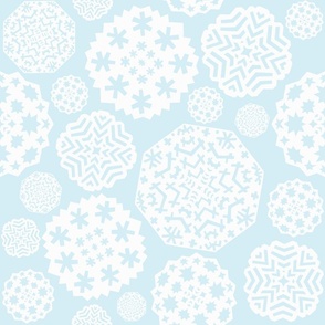Paper cut out white snowflakes on a light blue background