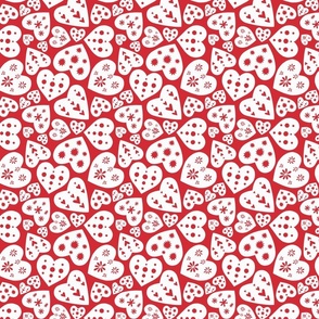 Minimal folk art paper cut out white hearts on a red background