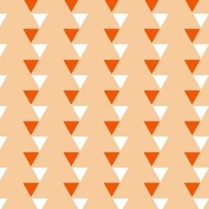 Off kilter small orange and white triangles against a peach background