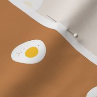 Breakfast for two - sunny side up eggs with salt and pepper yellow white on caramel burnt orange