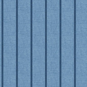 1/4" wide indigo denim pencil stripes on a chambray blue,  faux denim woven textured background. 