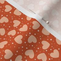 Small tossed Hearts with stars peach fuzz on rusty red | f6be9d