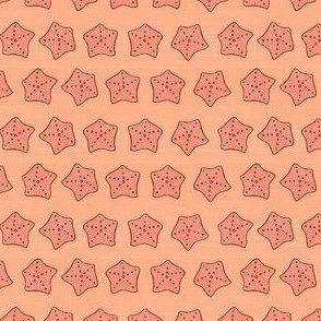 Small coral colored starfish on peach background