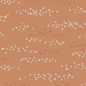 Hand drawn scattered white circles on ochre brown