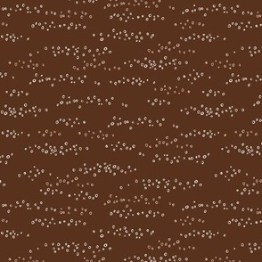 Hand drawn scattered white circles on dark chocolate brown