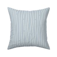 Vertical wavy lines of dots in a subtle nod to bubbles rising on a light blue background