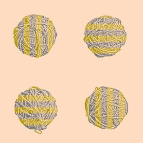 knitting a bumblebee:  stripey yarn balls in bronze and grey on peach