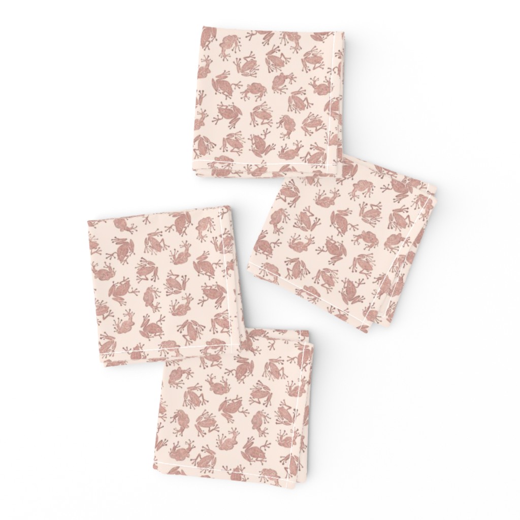 small terracotta frogs on pale pink