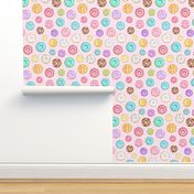 Scattered Rainbow Donuts on pale spotty pink - large scale