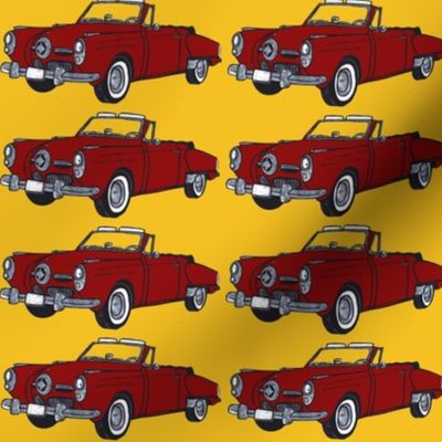 Red 1950 Studebaker convertible on yellow background