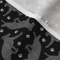 Tiny Trotting black German Shepherd dogs and paw prints - black