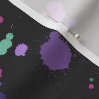Purple and green rainbow paint splatters on charcoal