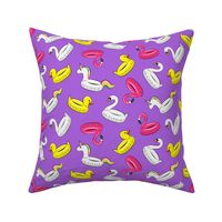 pool floats (swan, flaming, duck, unicorn) on purple